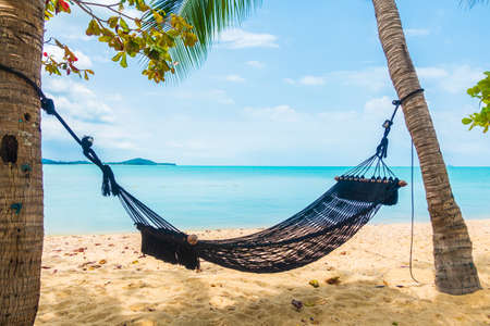 Empty hammock swing around beach sea ocean with white cloud blue sky for travel vacationの写真素材