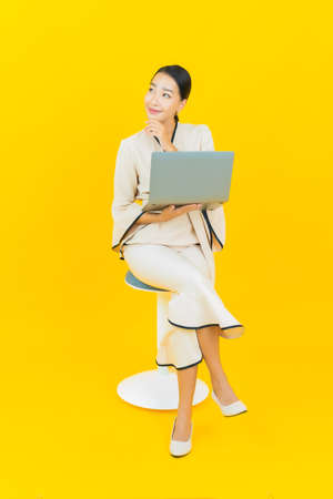 Portrait beautiful young business asian woman with smile and action yellow background