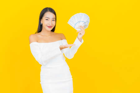 Portrait beautiful young business asian woman with a lot of cash money  on yellow backgroundの写真素材