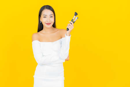 Portrait beautiful young business asian woman with smile and action yellow background