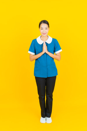 Portrait beautiful young asian woman smile with action on yellow color backgroundの写真素材