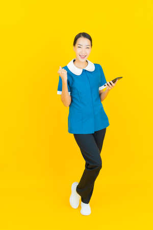 Portrait beautiful young asian woman smile with action on yellow color backgroundの写真素材