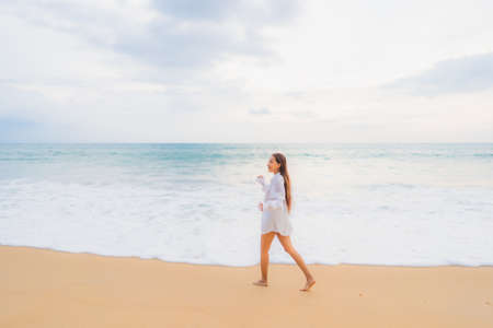 Portrait beautiful young asian woman relax smile leisure around sea beach ocean with white cloud on blue sky in travel vacationの写真素材