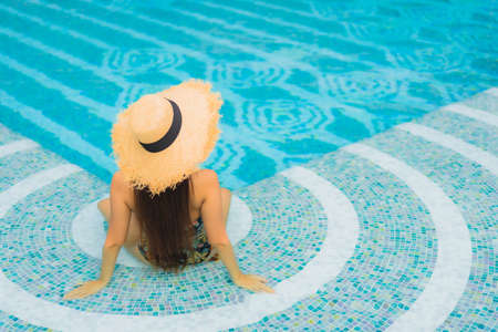 Portrait young asian woman read book around outdoor swimming pool in hotel resortの写真素材