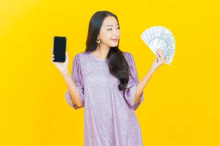 Portrait beautiful young asian woman smile with a lot of cash and money on color backgroundの写真素材