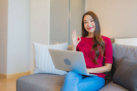 Portrait beautiful young asian woman relax smile in action on sofa in living room interior