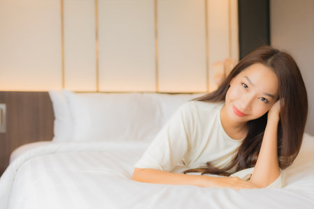 Portrait beautiful young asian woman smile relax leisure on bed in bedroom interiorの写真素材