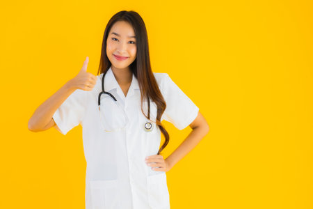 Portrait beautiful young asian doctor woman smile happy work in hospital and clinic on yellow isolated backgroundの写真素材