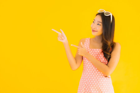 Portrait beautiful young asian woman smile happy on yellow isolated backgroundの写真素材