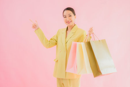Portrait beautiful young asian business woman with shopping bag on color isolated backgroundの写真素材