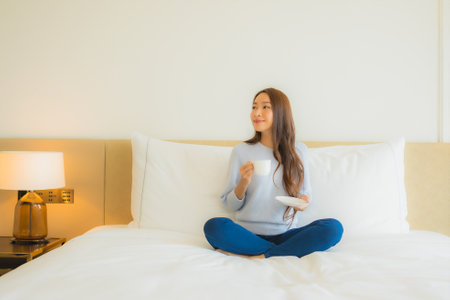 Portrait beautiful young asian woman relax smile leisure on bed in bedroom interiorの写真素材
