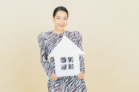 Portrait beautiful young asian woman with house or home paper sign on color backgroundの写真素材