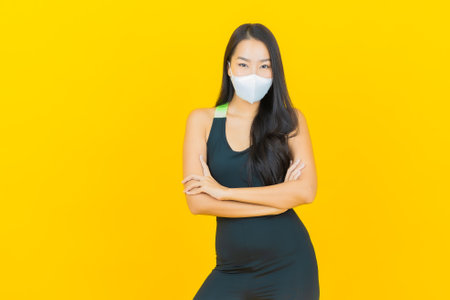Portrait beautiful young asian woman wear gym outfit ready for exercise on yellow color backgroundの写真素材