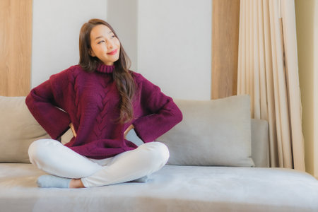 Portrait beautiful young asian woman smile relax on sofa in living room interiorの写真素材