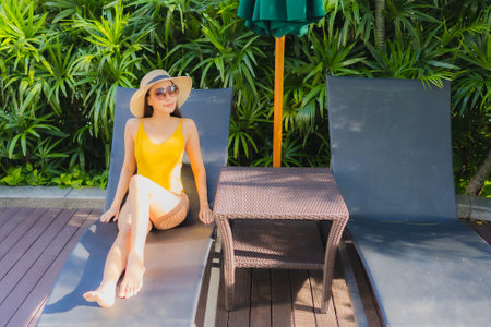 Portrait beautiful young asian woman relax happy smile around outdoor swimming pool in hotel resort for leisure vacationの写真素材
