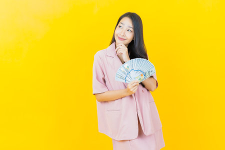 Portrait beautiful young asian woman smile with a lot of cash and money on color backgroundの写真素材