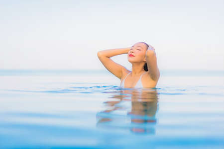 Portrait beautiful young asian woman relax smile around outdoor swimming pool in hotel resort nearly sea beach oceanの写真素材