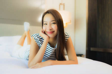 Portrait beautiful young asian woman use computer laptop on bed in bedroom interiorの写真素材