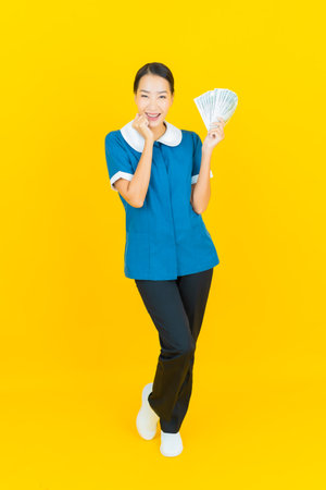 Portrait beautiful young asian woman maid and housekeeping smile with action on yellow color backgroundの写真素材