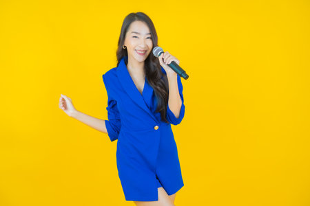 Portrait beautiful young asian woman use microphone for singing on color background