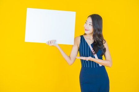 Portrait beautiful young asian woman with empty white billboard on color backgroundの写真素材