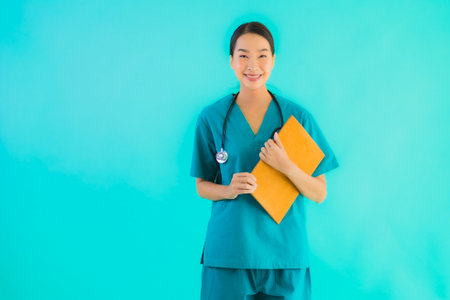 Portrait beautiful young asian doctor woman with empty paper board for copy space on blue isolated background - Healthcare in hospital and clinic conceptの写真素材