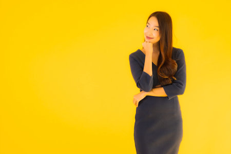 Portrait beautiful young asian woman with action on isolated yellow backgroundの写真素材