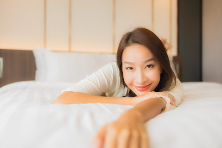 Portrait beautiful young asian woman smile relax leisure on bed in bedroom interiorの写真素材