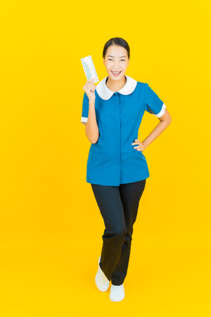 Portrait beautiful young asian woman maid and housekeeping smile with action on yellow color backgroundの写真素材