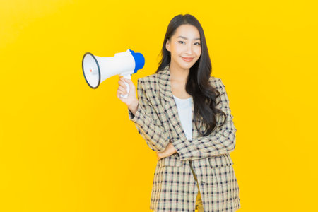Portrait beautiful young asian woman smile with megaphone on color backgroundの写真素材
