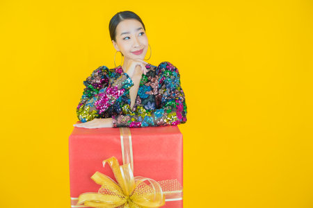 Portrait beautiful young asian woman smile with red gift box on color backgroundの写真素材