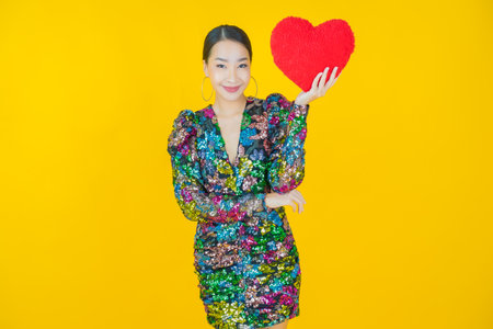 Portrait beautiful young asian woman smile with heart pillow shape on color backgroundの写真素材