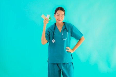 Portrait beautiful young asian doctor woman with pill or drug and medicine on blue isolated backgroundの写真素材