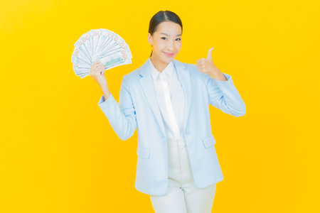 Portrait beautiful young asian woman smile with a lot of cash and money on color backgroundの写真素材
