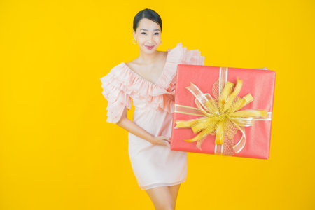 Portrait beautiful young asian woman smile with red gift box on color backgroundの写真素材