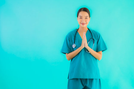 Portrait beautiful young asian doctor woman happy smile with sawasdee for work in hospital and clinic on blue isolated backgroundの写真素材