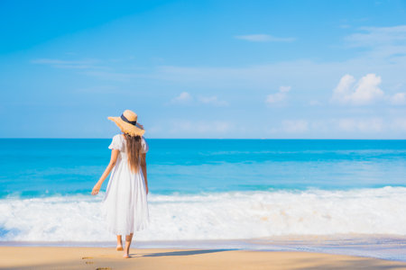 Portrait beautiful young asian woman relax smile leisure around sea beach ocean with white cloud on blue sky in travel vacationの写真素材