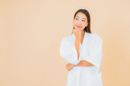 Portrait beautiful young asian woman wear bathrobe with smile on color backgroundの写真素材