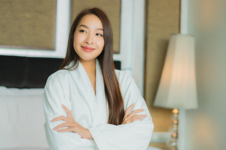 Portrait beautiful young asian woman smile relax on bed in bedroom interiorの写真素材