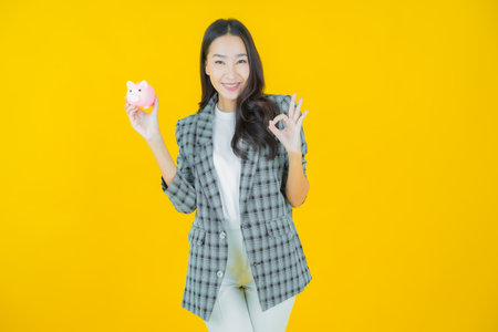 Portrait beautiful young asian woman with piggy bank on color backgroundの写真素材