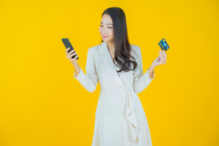 Portrait beautiful young asian woman smile with credit card on color backgroundの写真素材