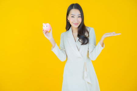 Portrait beautiful young asian woman with piggy bank on color backgroundの写真素材