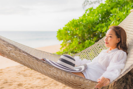 Portrait beautiful young asian woman relax on hammock around beach sea ocean for leisure in vacationの写真素材