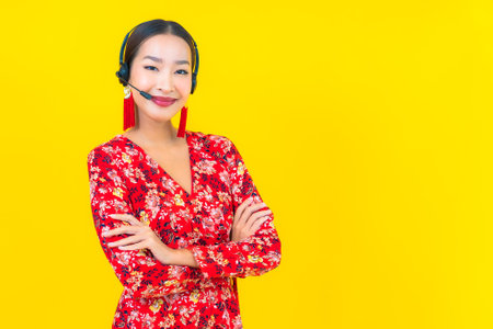 Portrait beautiful young asian woman with headset for customer call center care on yellow backgroundの写真素材