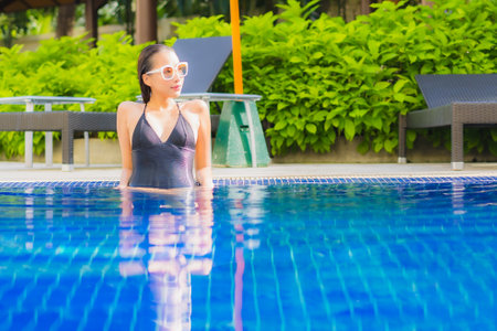 Portrait beautiful young asian woman smile relax leisure around outdoor swimming pool in hotel resortの写真素材