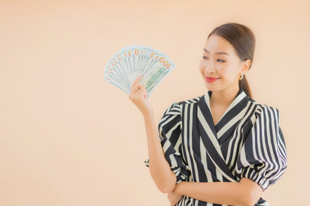 Portrait beautiful young asian woman with cash and money on brown backgroundの写真素材