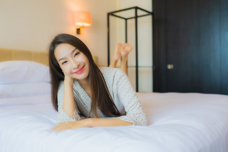 Portrait beautiful young asian woman smile happy relax on bed in bedroom interiorの写真素材