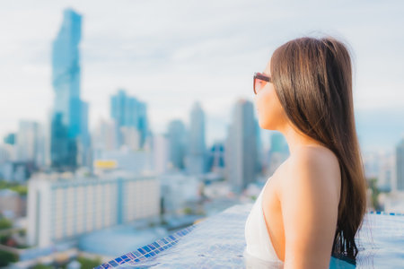 Portrait beautiful young asian woman relax happy smile leisure around outdoor swimming pool with cityscapeの写真素材