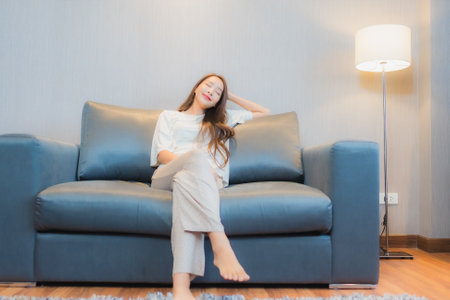 Portrait beautiful young asian woman relax on sofa in living room interiorの写真素材