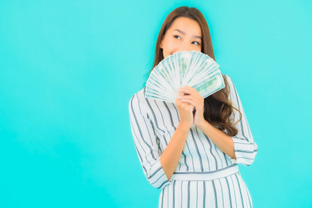 Portrait beautiful young asian woman with a lot of cash and money on blue backgroundの写真素材